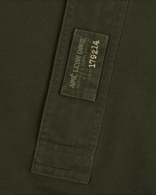 Garment Washed Anorak in olive green with a rectangular patch featuring branded text and the number 179214.