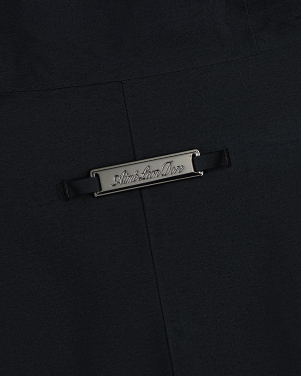 A rectangular metallic silver Aimé Leon Dore plaque attached to black fabric on a GORE-TEX Down Filled Fishtail Parka.