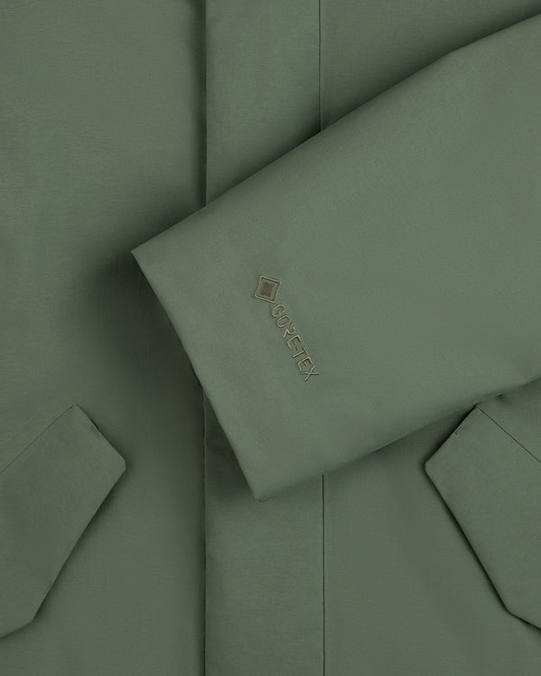 Olive green sleeve of a GORE-TEX Down Filled Fishtail Parka featuring an embroidered logo on the cuff.
