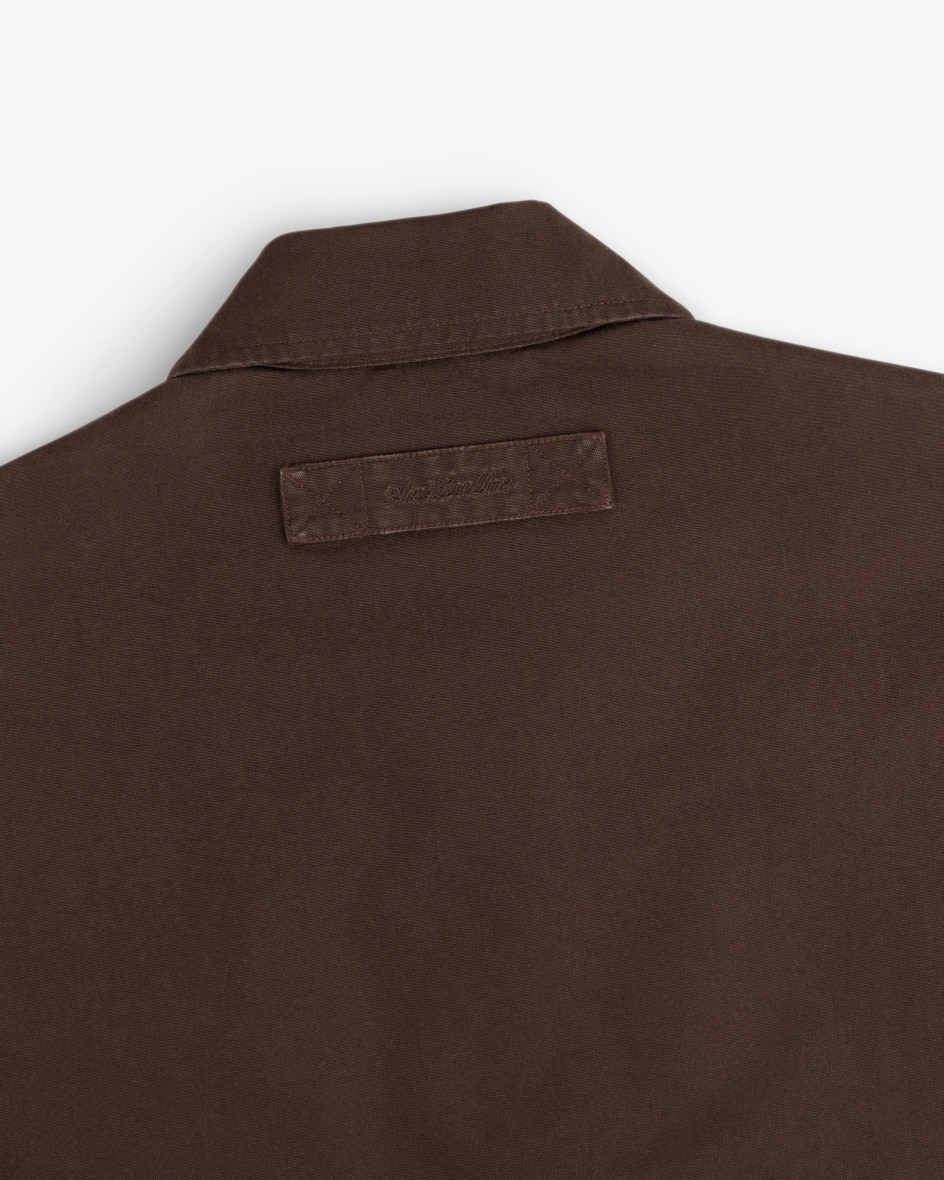 Close-up of the back collar and rectangular fabric label on a brown Fleece Lined Mechanic Jacket.
