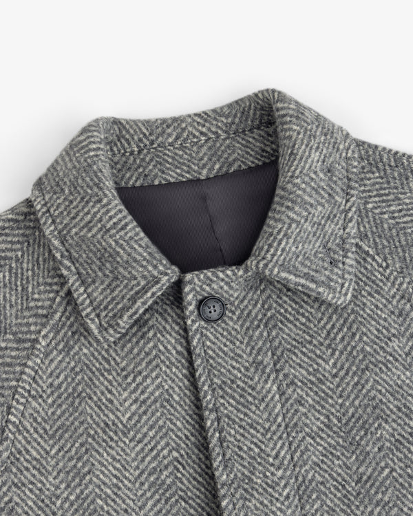 Close-up of a grey Wool Herringbone Overcoat featuring a pointed collar and a single front button.