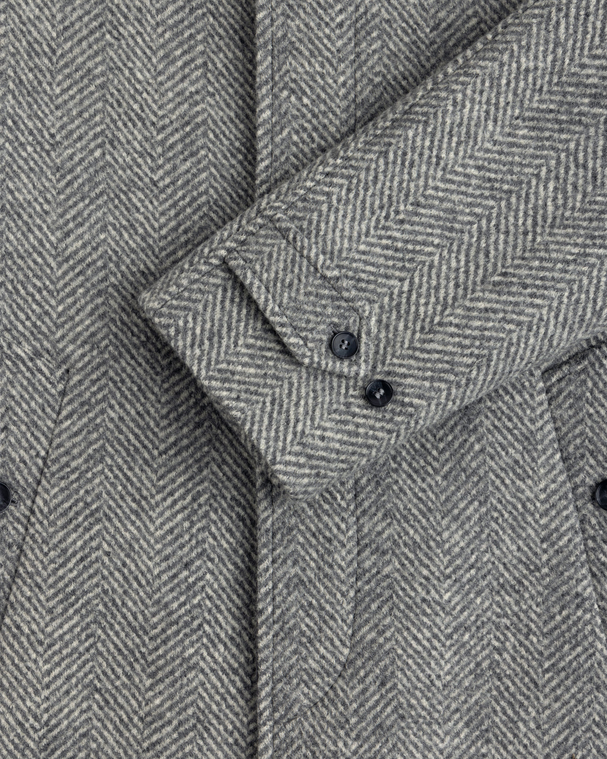 Wool Herringbone Overcoat sleeve in gray herringbone with two dark buttons.