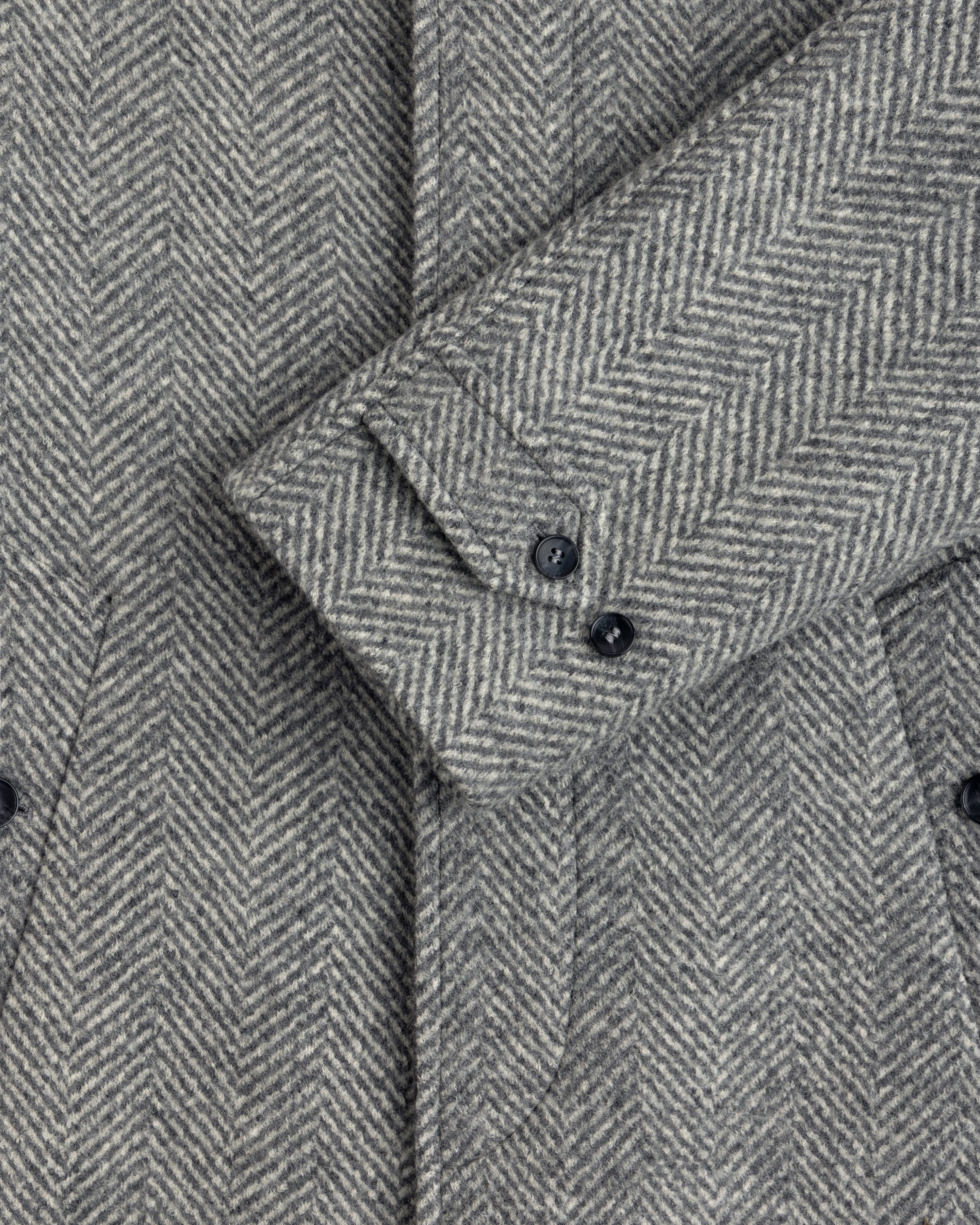 Wool Herringbone Overcoat sleeve in gray herringbone with two dark buttons.