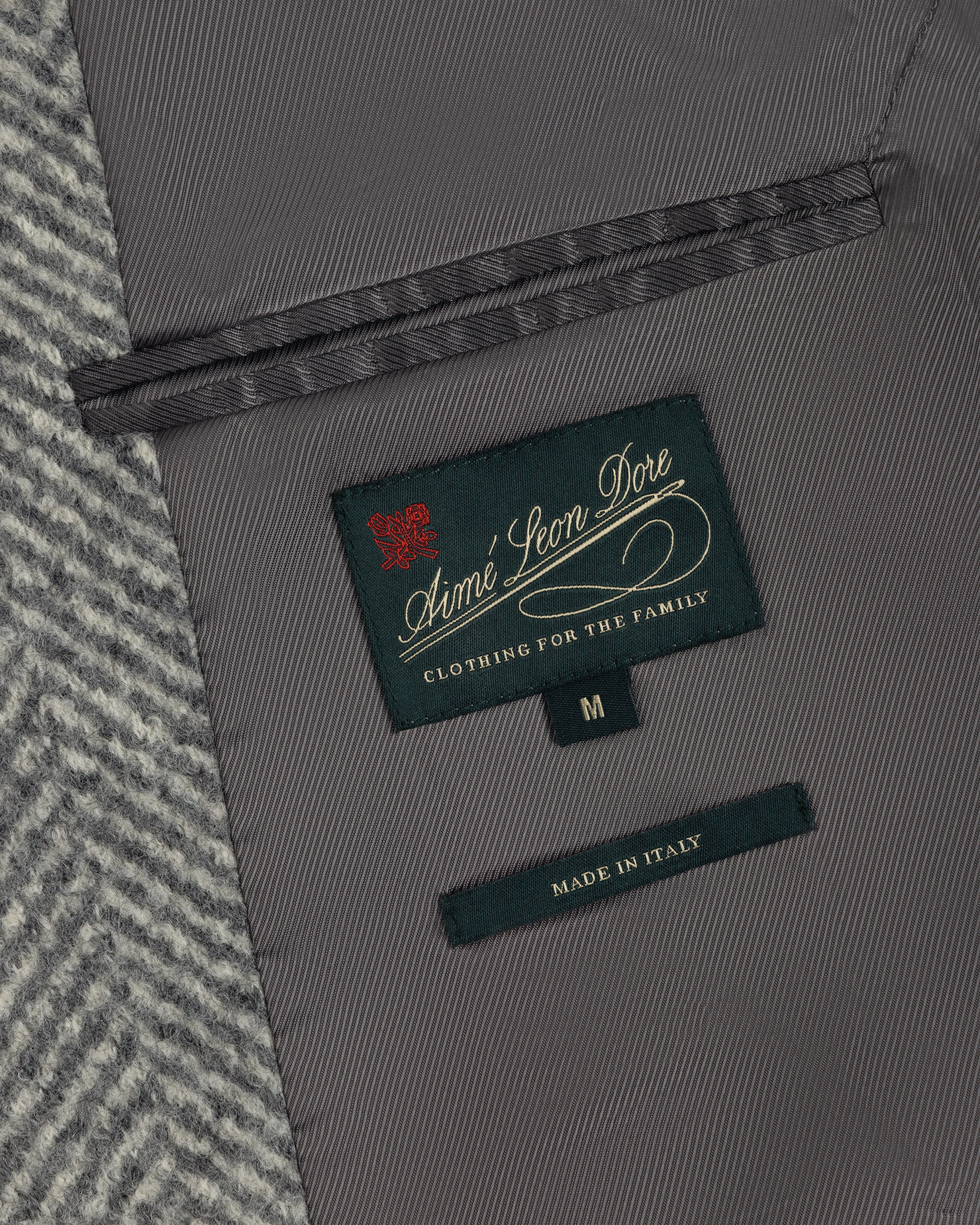 Close-up of the grey Wool Herringbone Overcoat interior, showing a branded label, size M tag, and Made in Italy label.