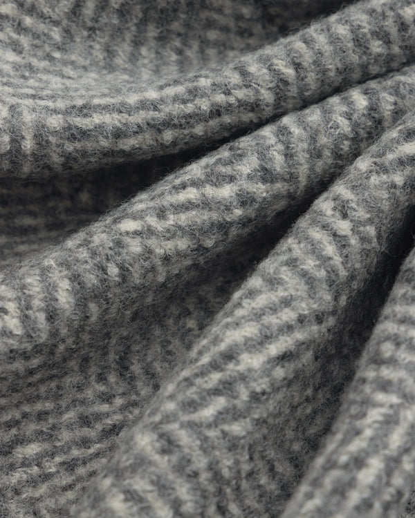 Close-up of a grey and white Wool Herringbone Overcoat in folded fabric.