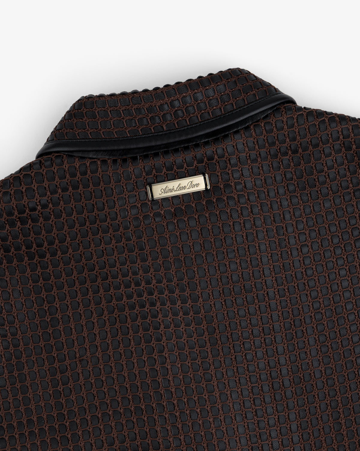 Close-up of a brown and black Woven Leather Jacket collar with a metallic brand tag at the neckline.