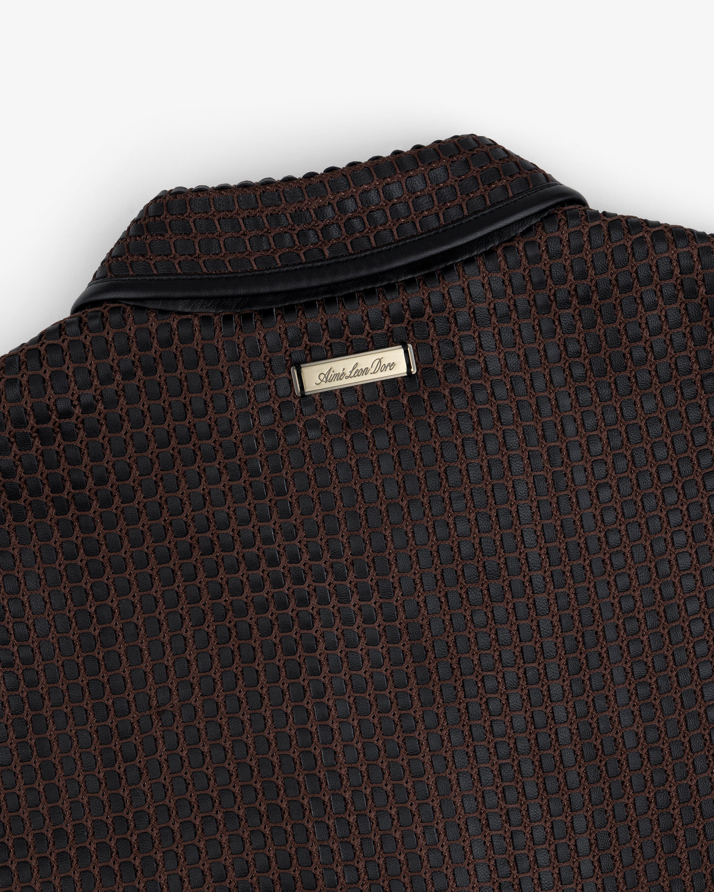 Close-up of a brown and black Woven Leather Jacket collar with a metallic brand tag at the neckline.