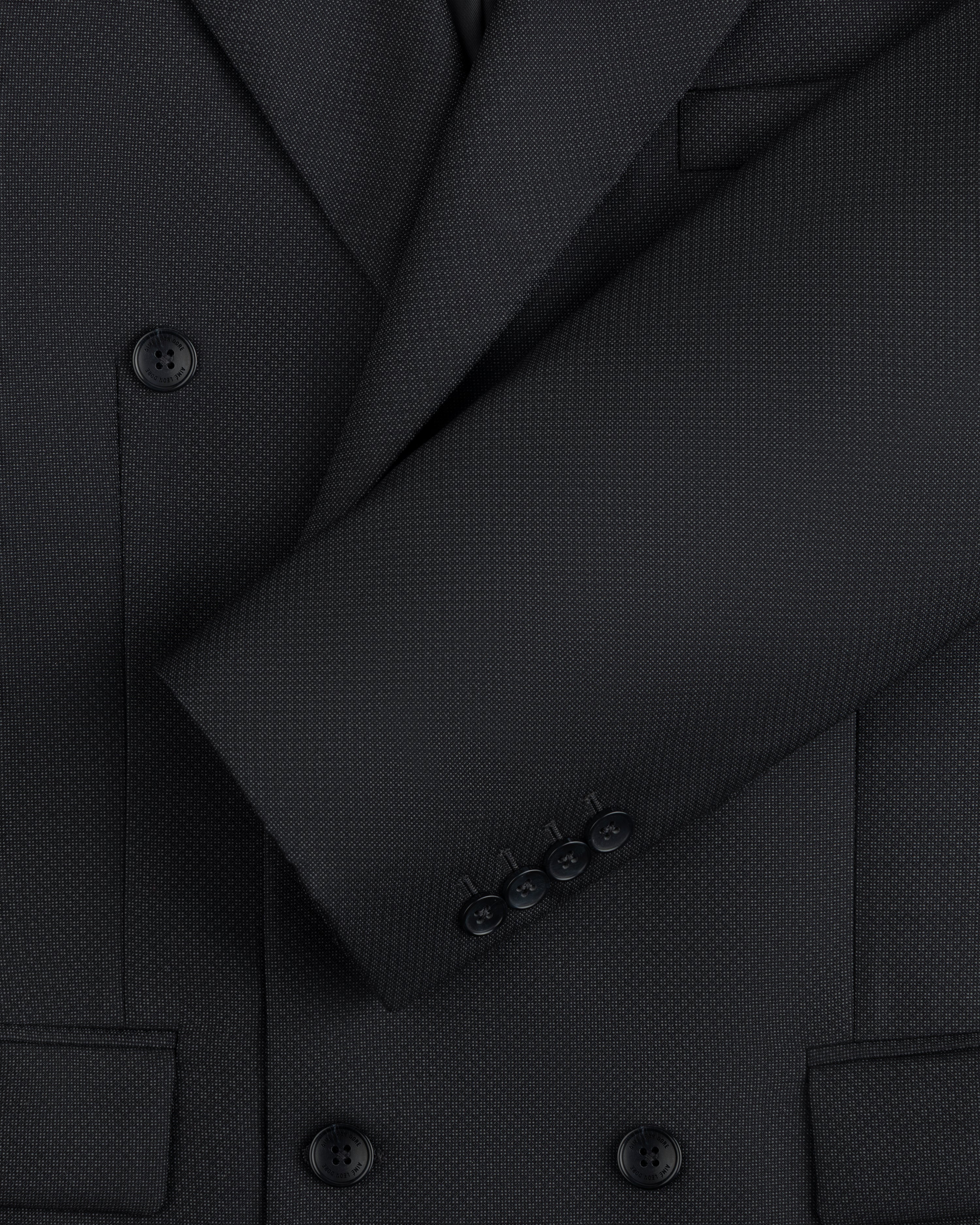Close-up of a charcoal Double-Breasted Wool Jacquard Suit Jacket with buttoned sleeves and textured fabric.