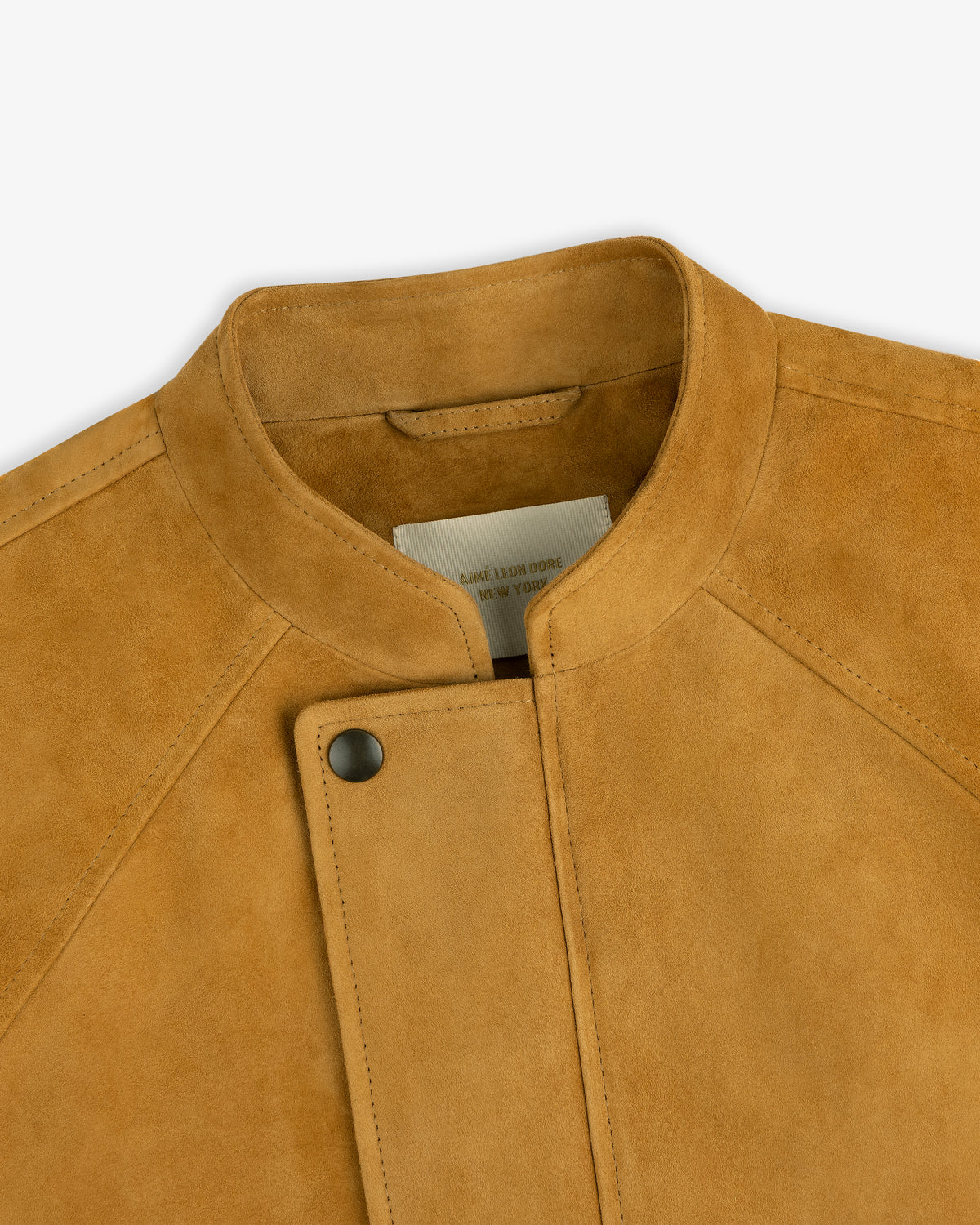 Close-up of the Suede Cafe Racer Jacket in tan, featuring a snap button, standing collar, and partial interior label.
