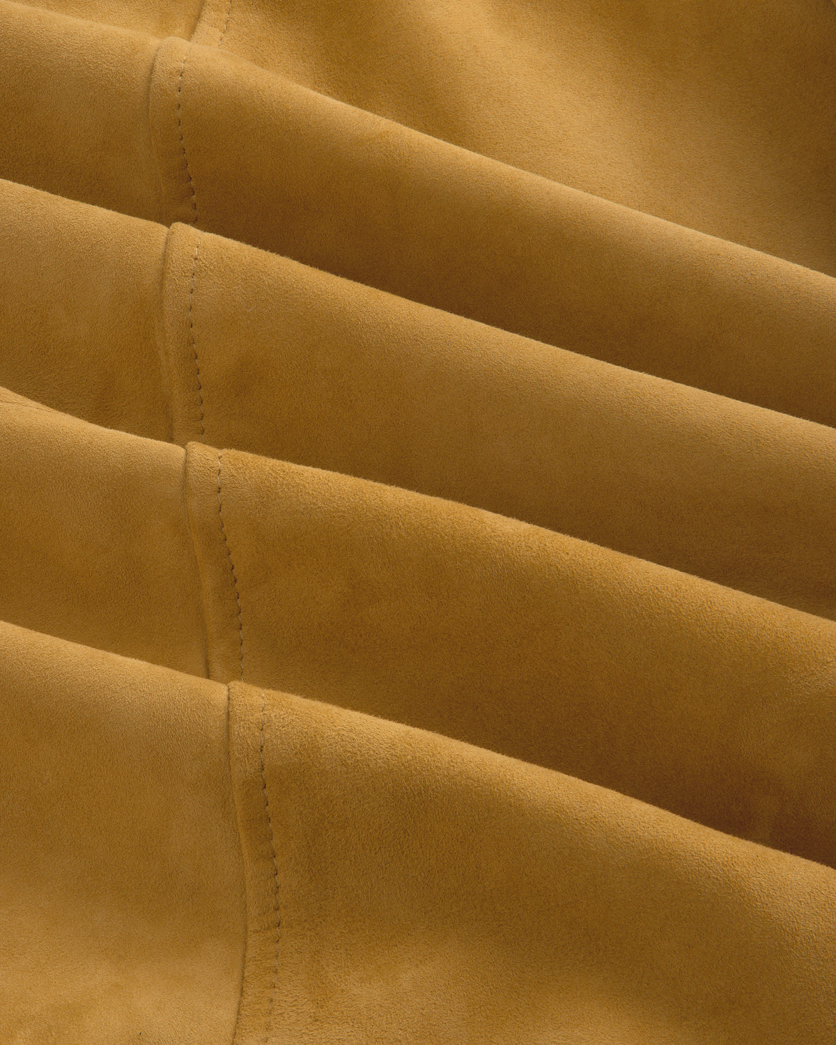 Detail of the Suede Cafe Racer Jacket’s tan suede fabric with parallel stitched seams for a textured look.