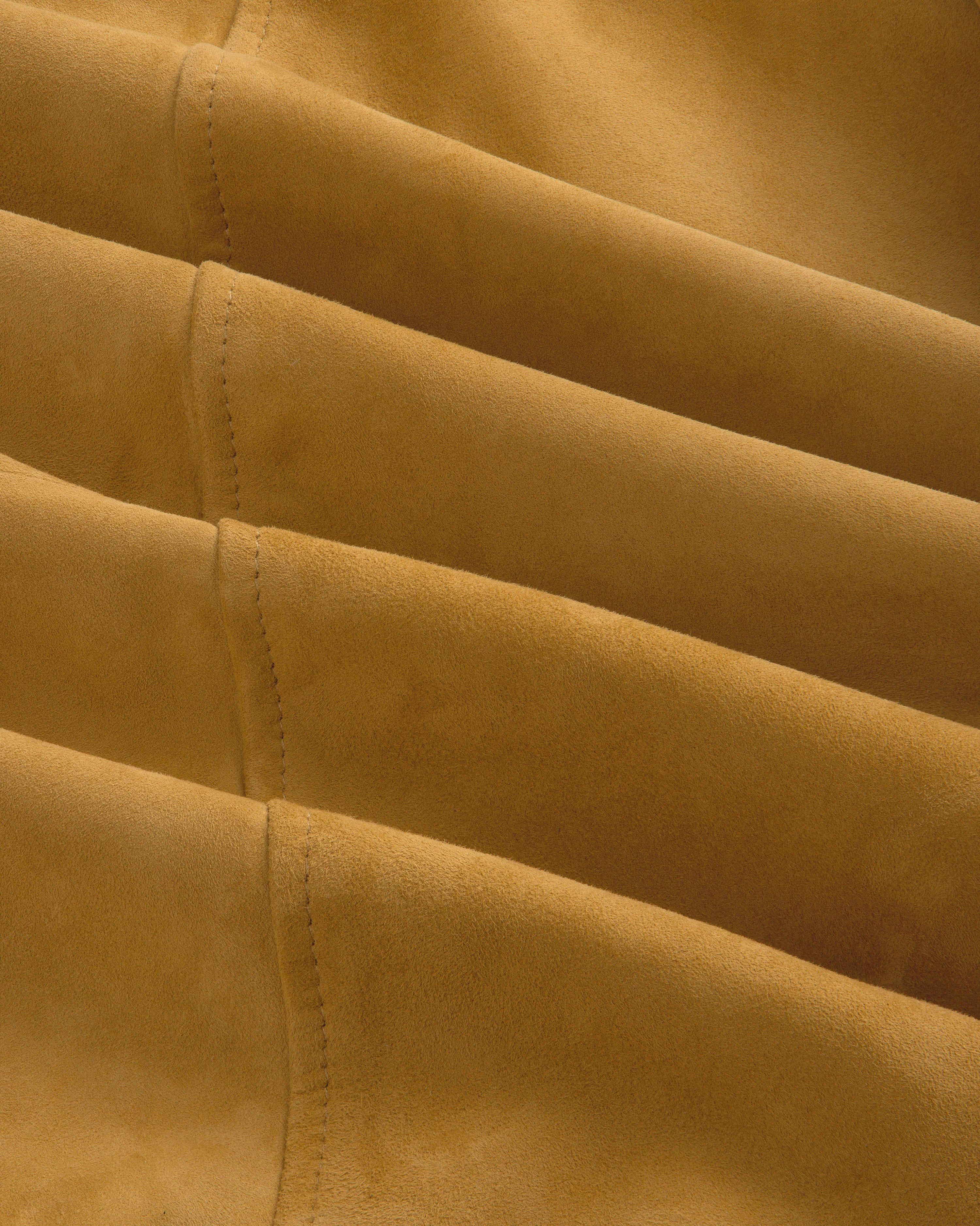 Detail of the Suede Cafe Racer Jacket’s tan suede fabric with parallel stitched seams for a textured look.