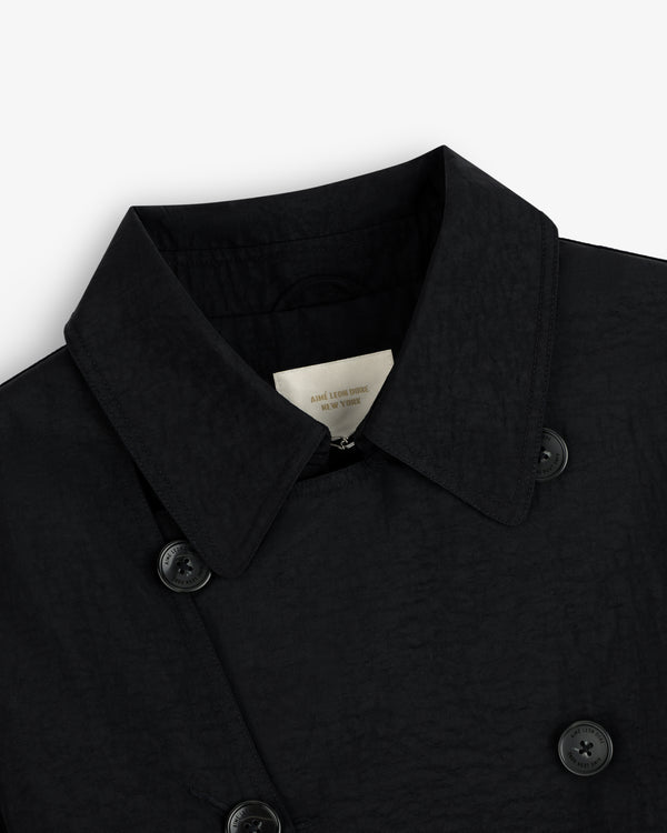 Close-up of a black Double Breasted Nylon Trench Coat with buttons and inner label, on a white background.