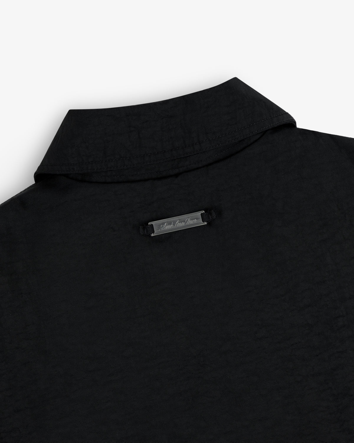 Close-up of the back collar of a nylon trench coat with a small metallic label below the collar.