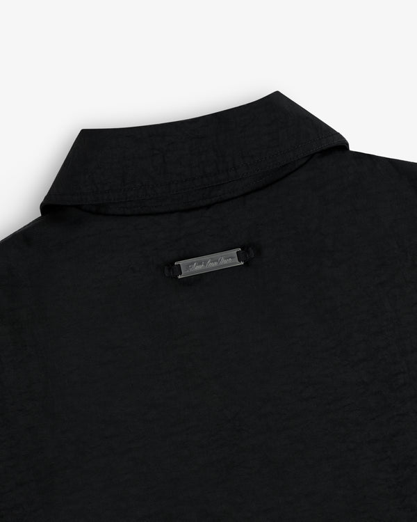 Close-up of the back collar of a nylon trench coat with a small metallic label below the collar.