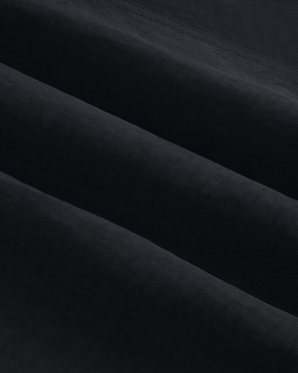 Close-up of Double Breasted Nylon Trench Coat fabric, showing its textured black material with subtle diagonal folds.