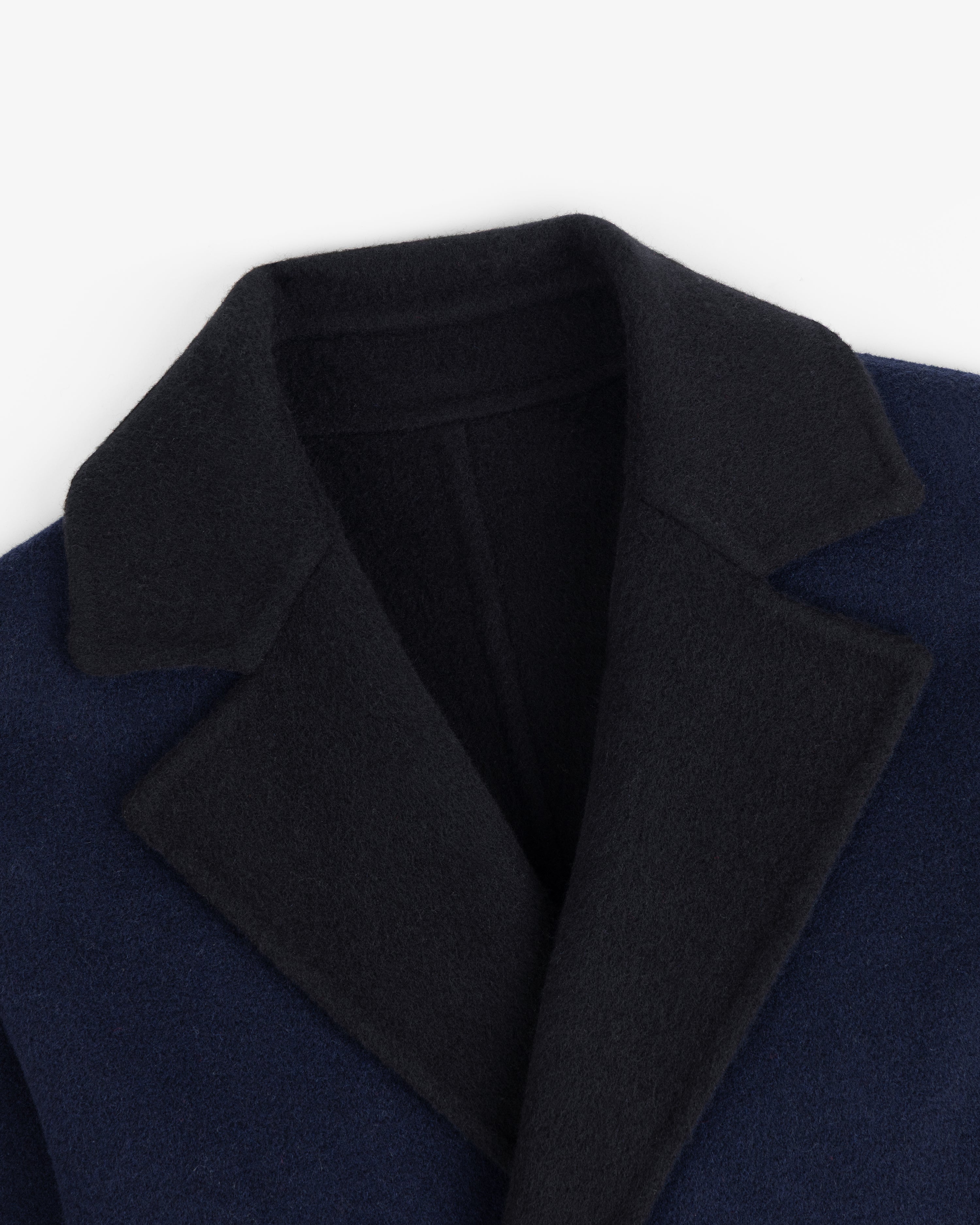 Close-up of a Reversible Double Breasted Top Coat with a dark navy body and a black notch lapel collar.