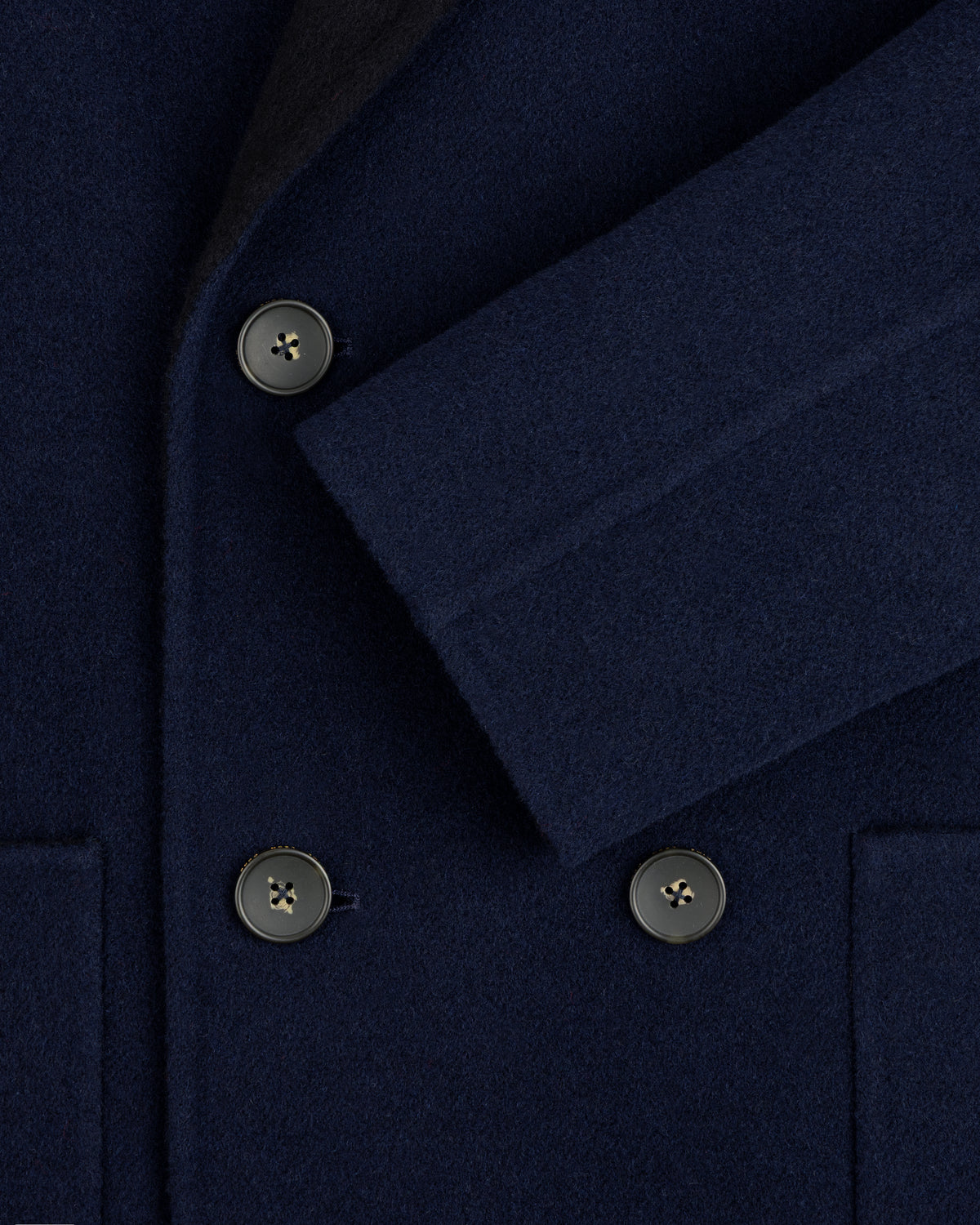 Close-up of a navy blue Reversible Double Breasted Top Coat with dark buttons.