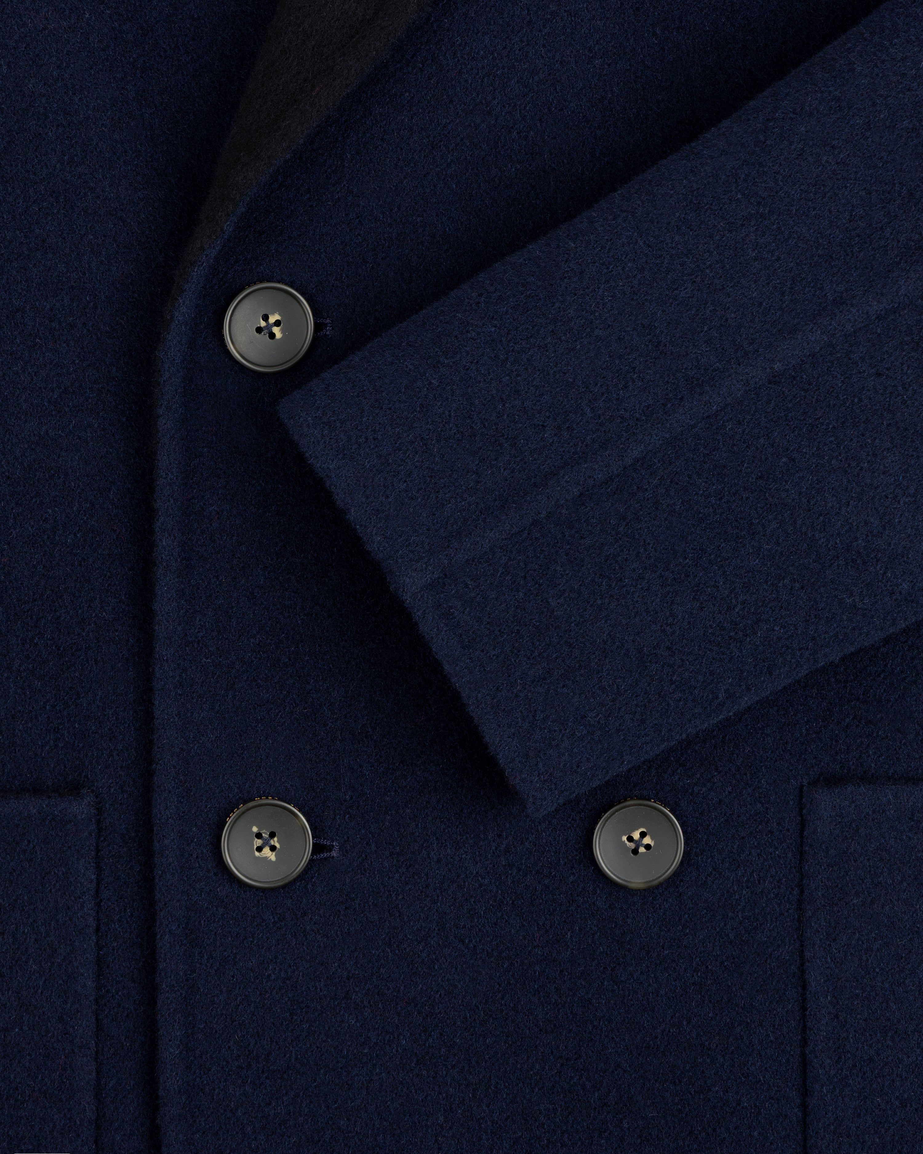 Close-up of a navy blue Reversible Double Breasted Top Coat with dark buttons.