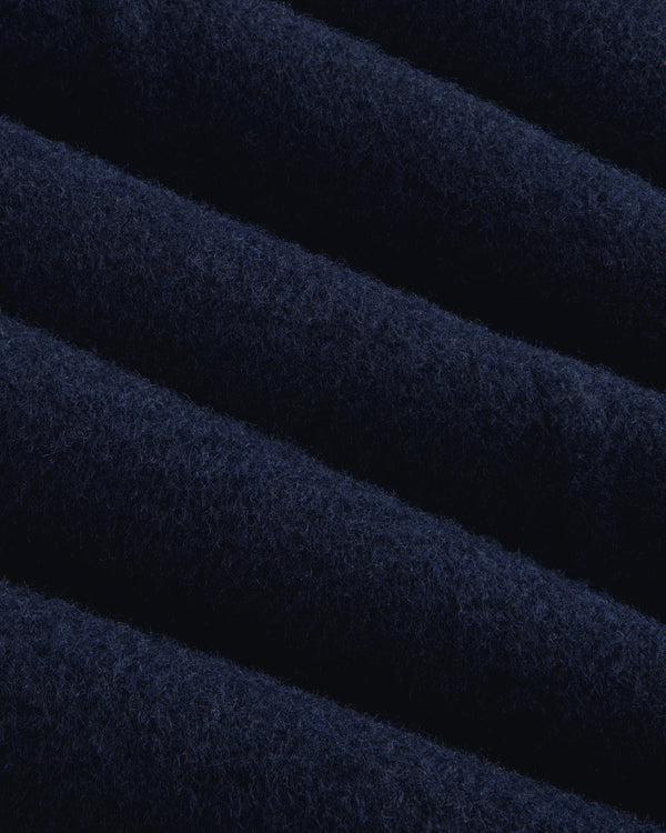 Close-up of navy blue wool fabric with diagonal folds on a Reversible Double Breasted Top Coat.