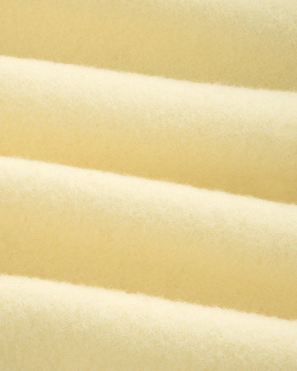 Close-up of the thick, cream-colored fabric of a Wool Sportcoat, featuring soft, folded ridges.