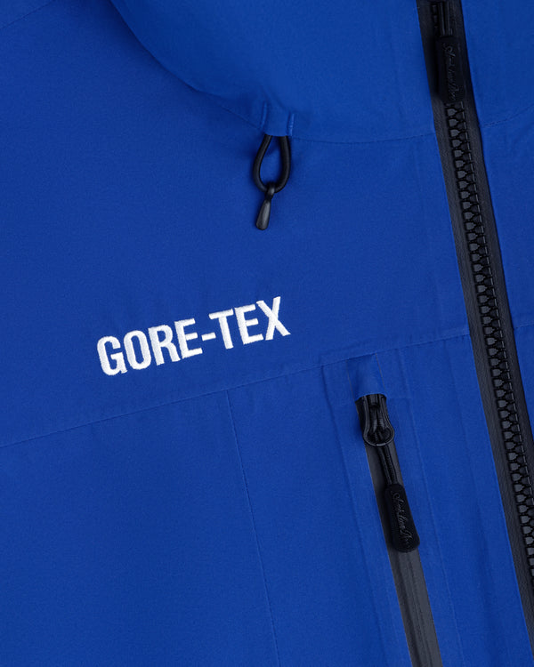 Bright blue Cropped GORE-TEX Shell Jacket with a white logo and black zippered chest pocket.