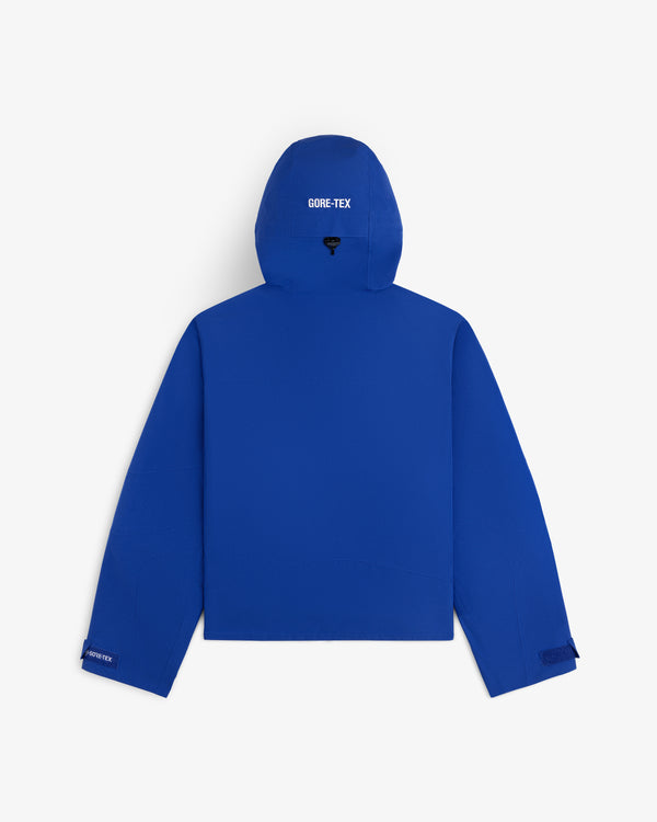 Back view of a blue Cropped GORE-TEX Shell Jacket with branding on the hood and sleeve.