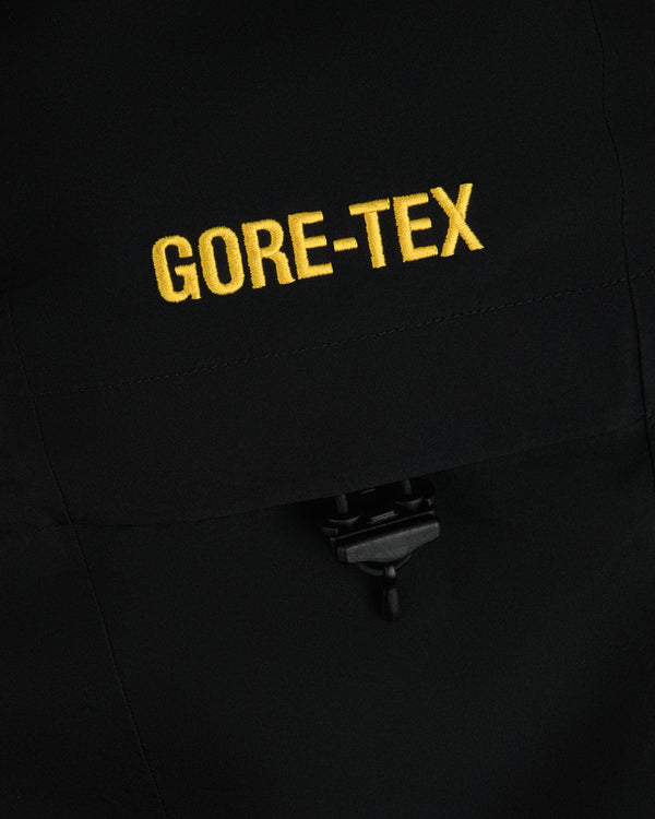 Yellow GORE-TEX embroidery on a black Cropped GORE-TEX Shell Jacket with a drawstring toggle.