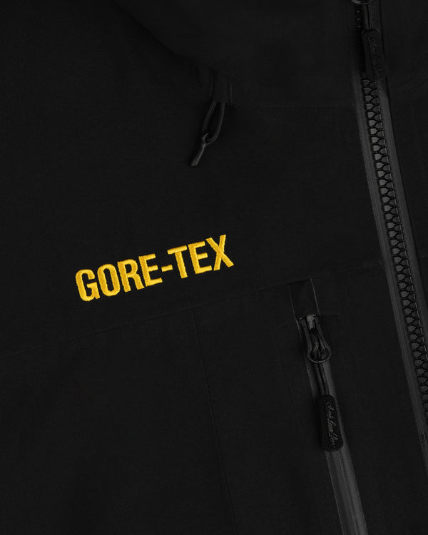 Cropped GORE-TEX Shell Jacket in black, featuring a zippered pocket and yellow GORE-TEX embroidery.