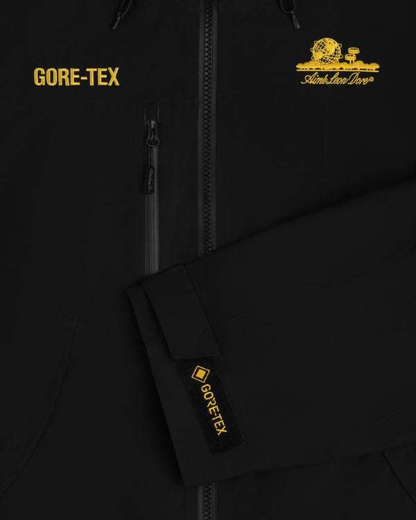 Black Cropped GORE-TEX Shell Jacket with yellow text, a chest pocket, and a brand logo featuring a globe graphic.