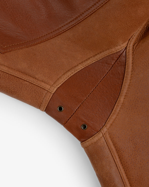 Close-up of a brown Shearling Bomber Jacket showing stitched panel seams and two metal eyelets.