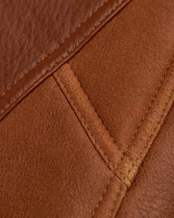 Close-up of brown leather and suede panels on a Shearling Bomber Jacket joined by stitched seams.