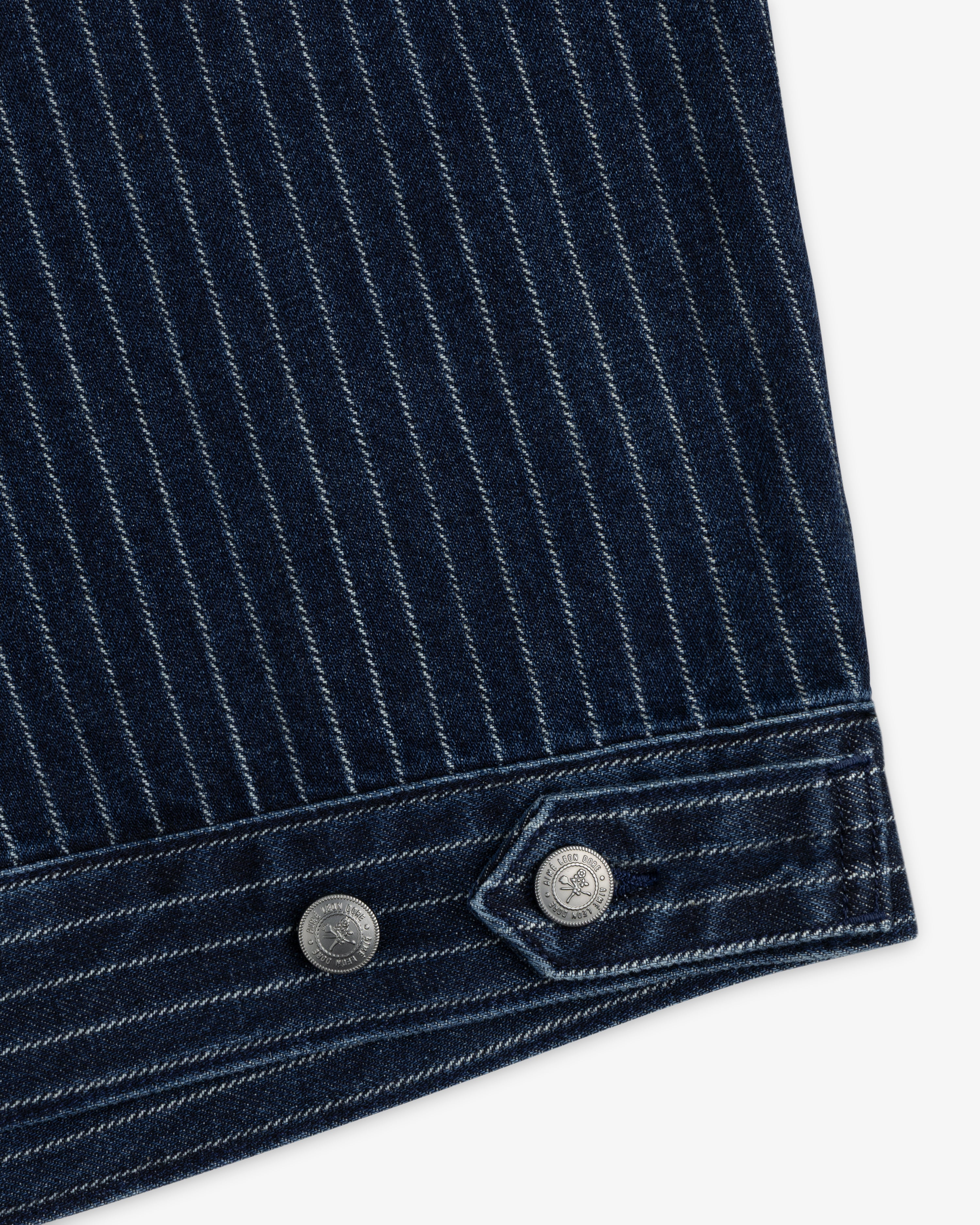 Close-up of Chalk Stripe Denim Trucker Jacket in dark blue pinstripe with two silver buttons on the cuff.
