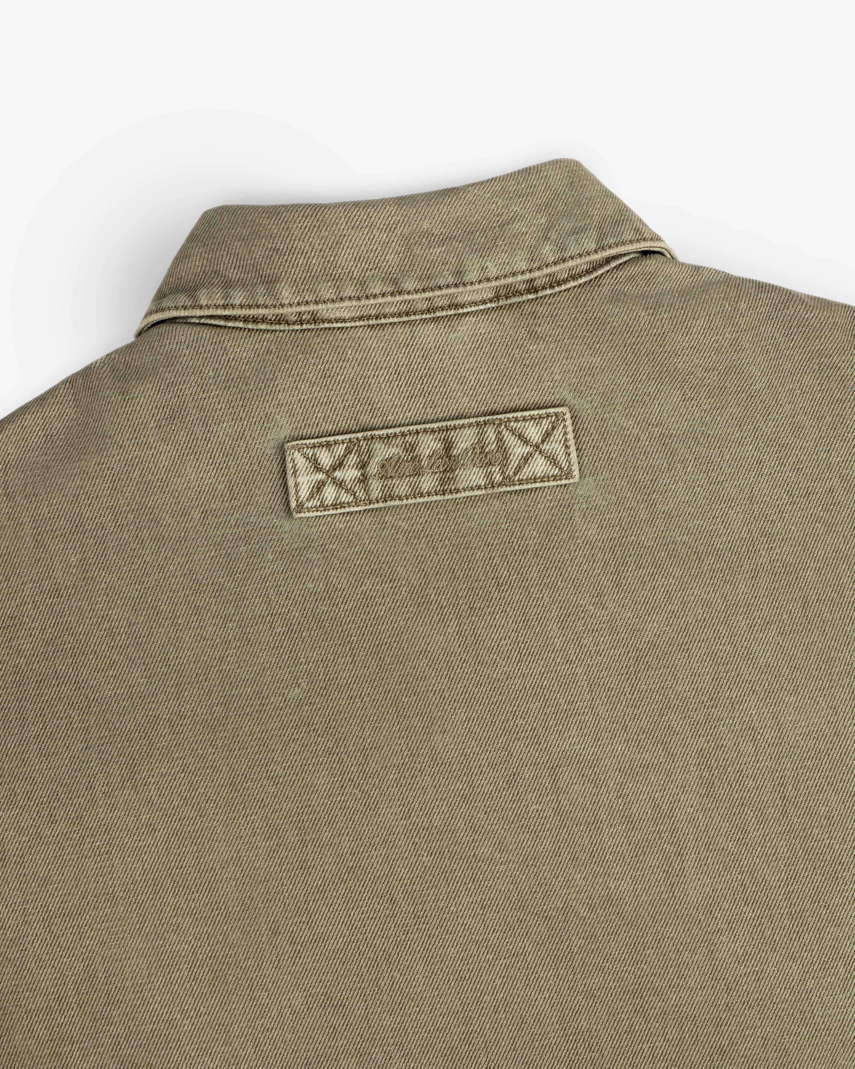 Close-up of the back collar and rectangular brand patch on a tan Flocked Denim Jacket.