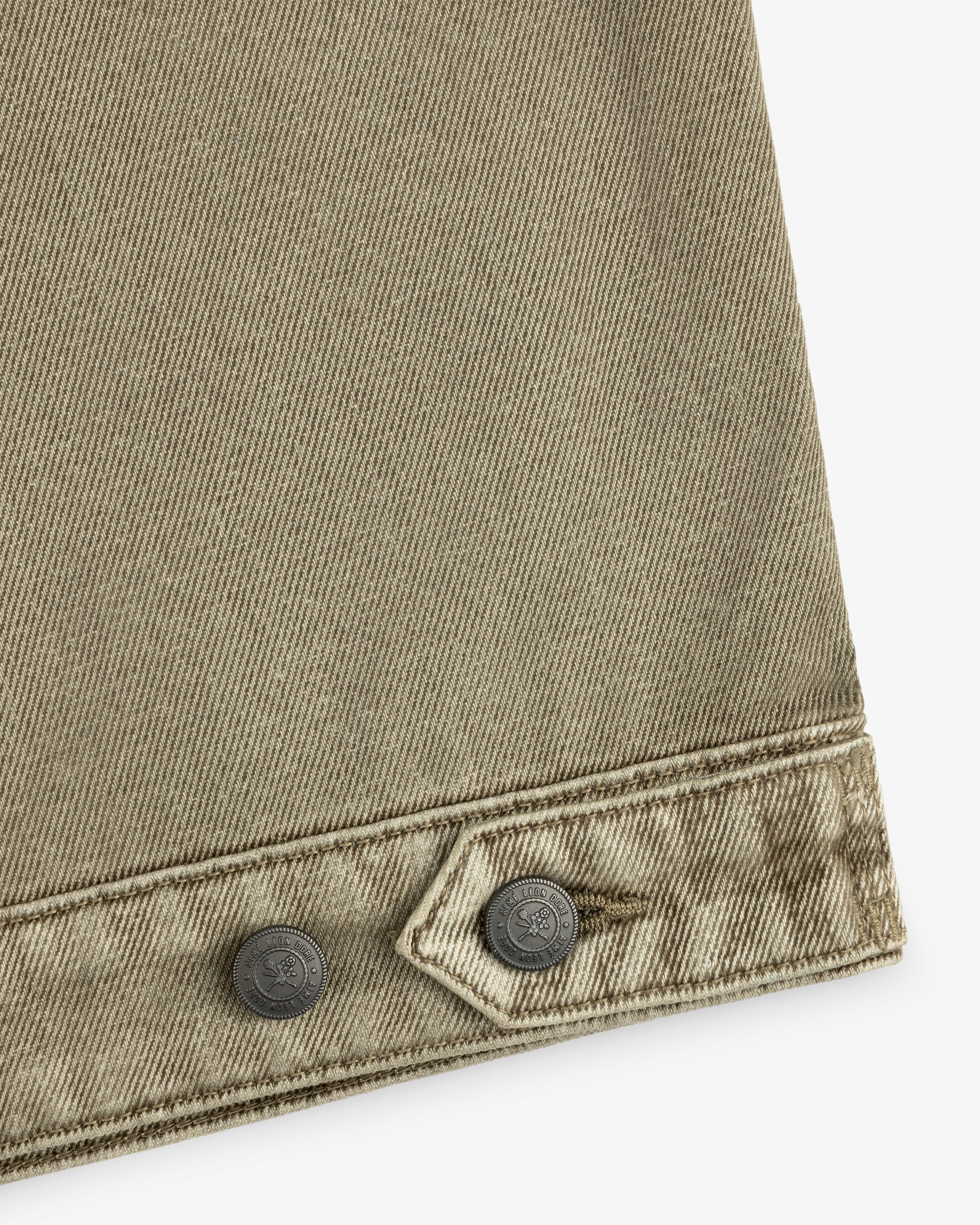 Close-up of olive green Flocked Denim Jacket fabric featuring a buttoned tab at the hem.
