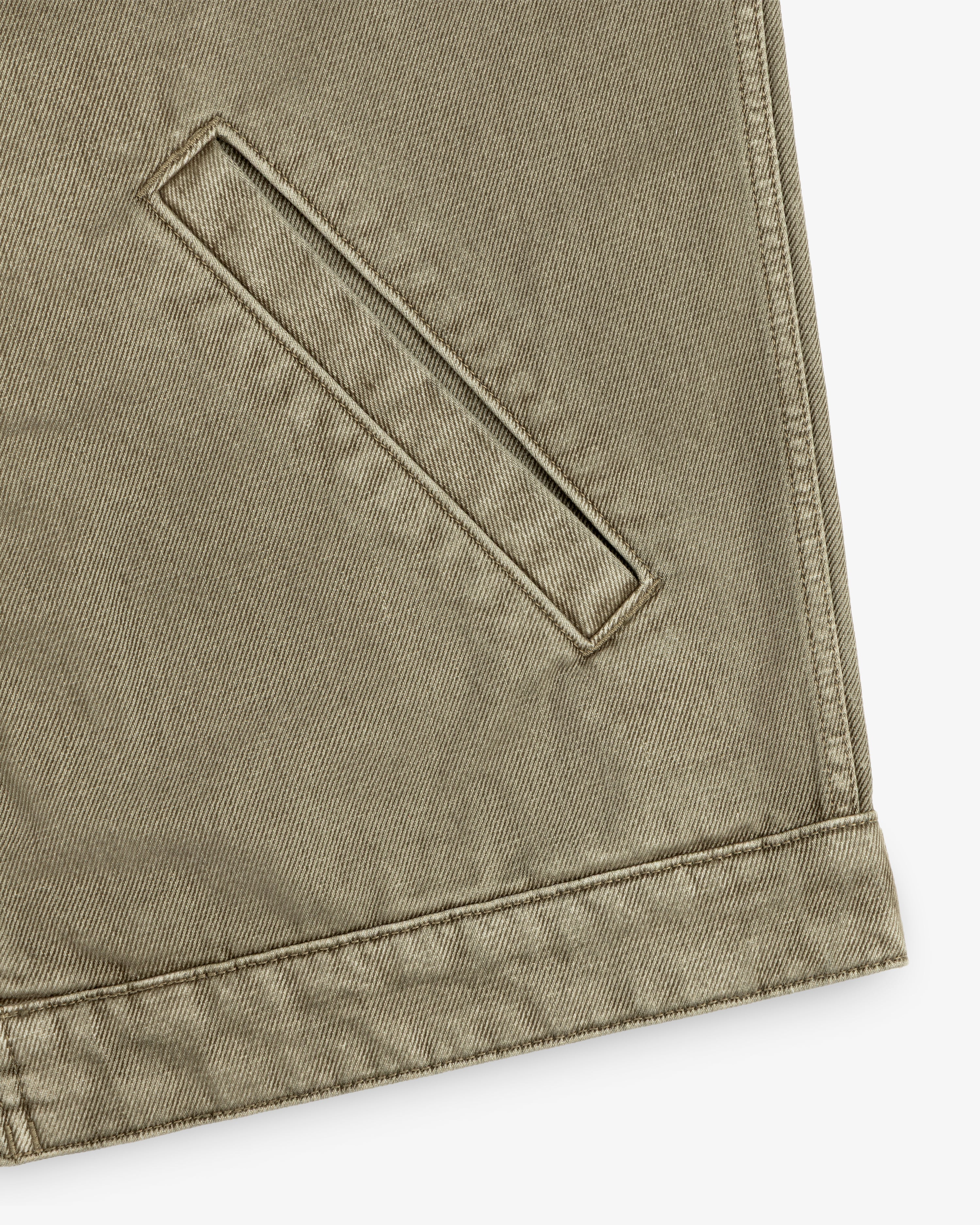 Close-up of a brown Flocked Denim Jacket featuring a welt pocket and a stitched waistband.