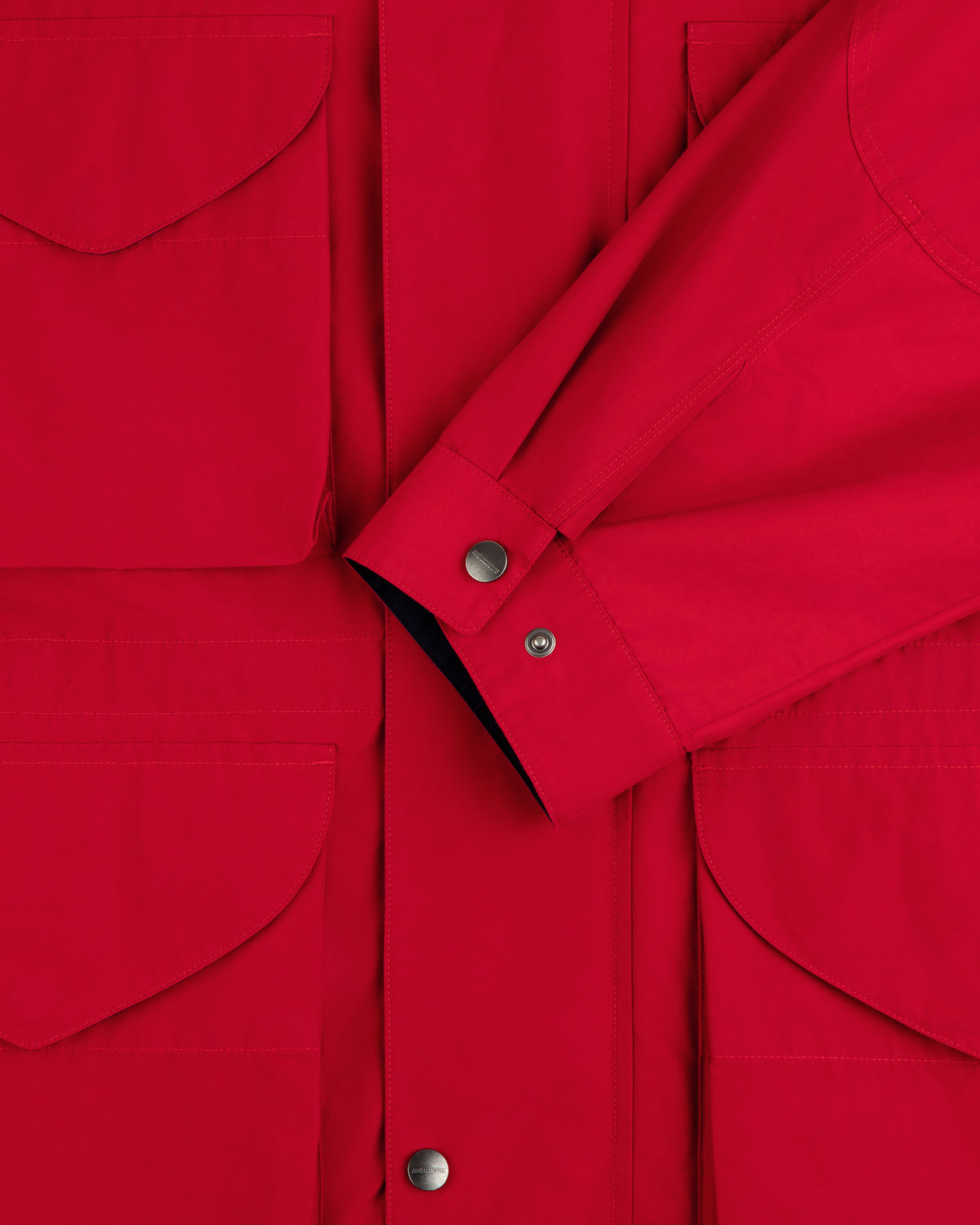 Close-up of the Lightweight Barn Jacket in red, featuring flap pockets, snap buttons, and a crossed sleeve detail.