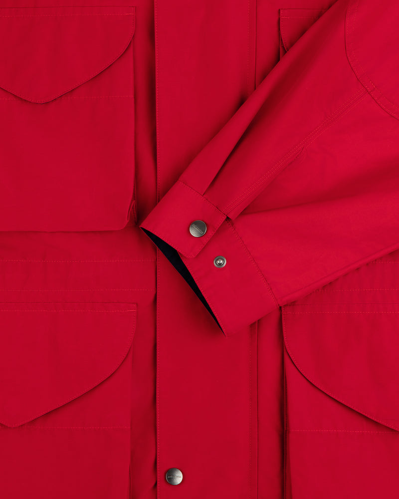 Close-up of the Lightweight Barn Jacket in red, featuring flap pockets, snap buttons, and a crossed sleeve detail.