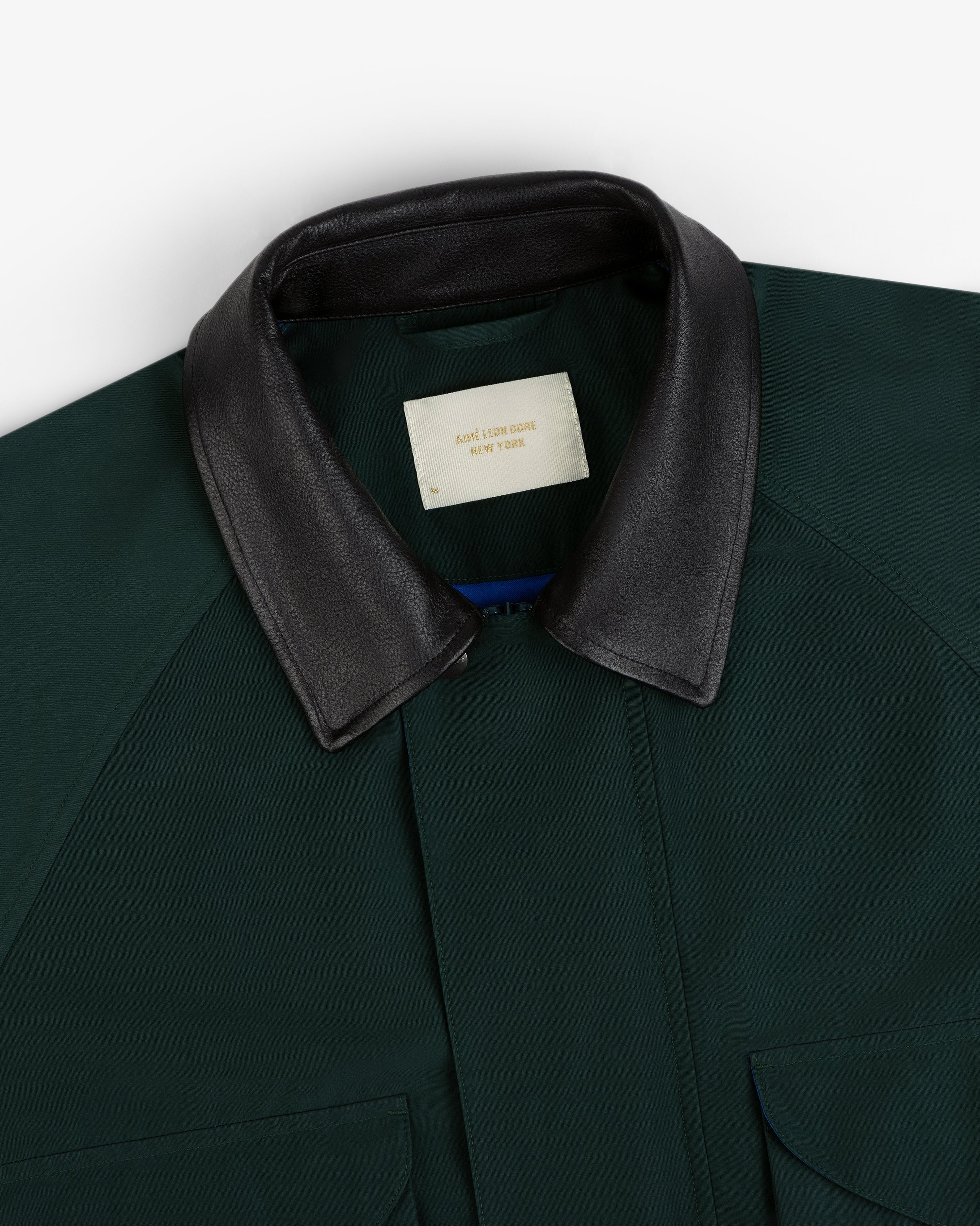 Dark green Lightweight Barn Jacket with black leather collar and cream Aime Leon Dore New York label.