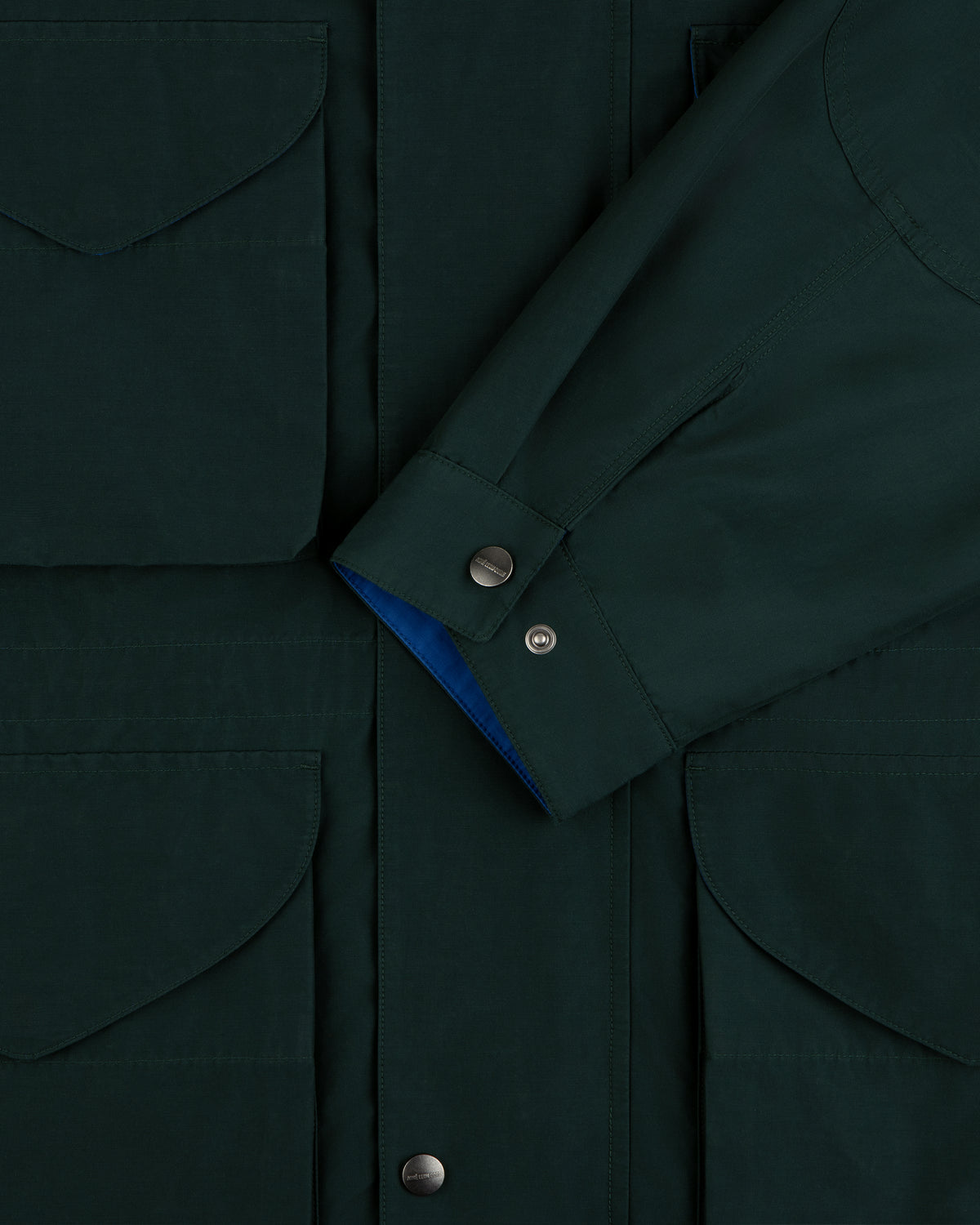 Lightweight Barn Jacket in dark green, close-up of pocket flaps, snap buttons, and overlapping sleeve.