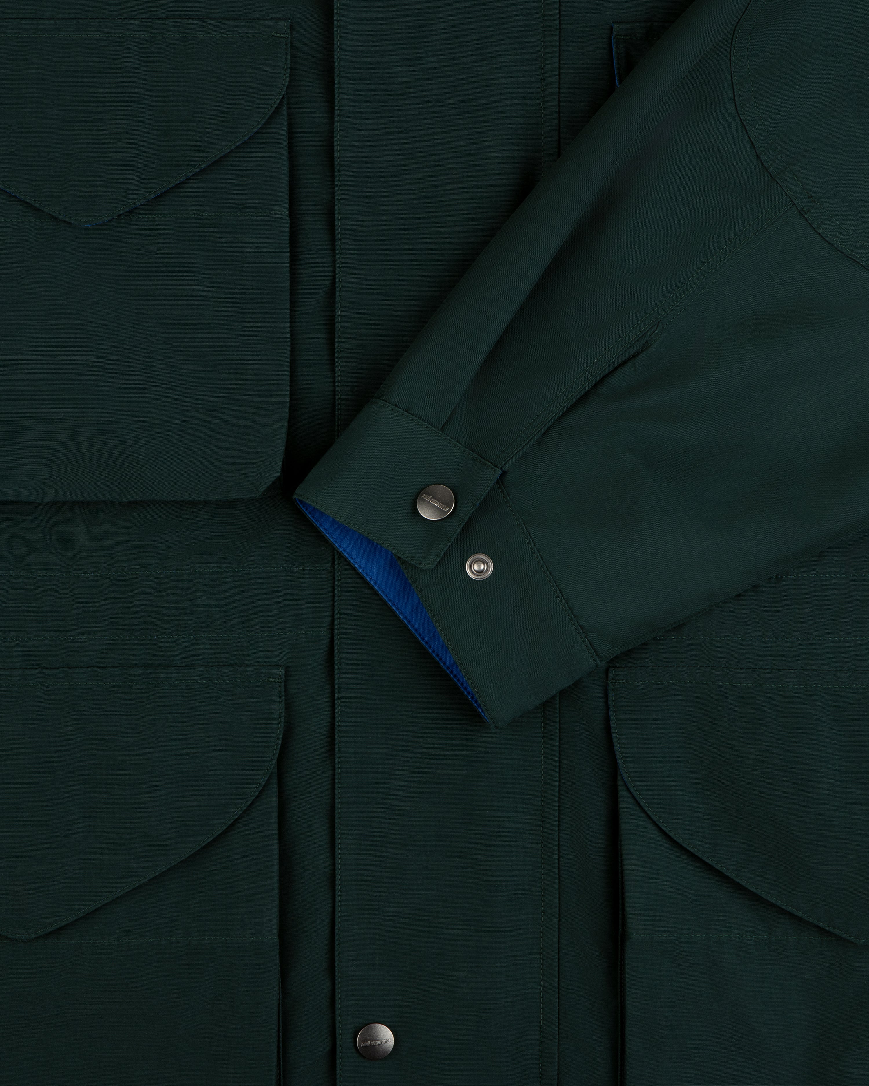 Lightweight Barn Jacket in dark green, close-up of pocket flaps, snap buttons, and overlapping sleeve.