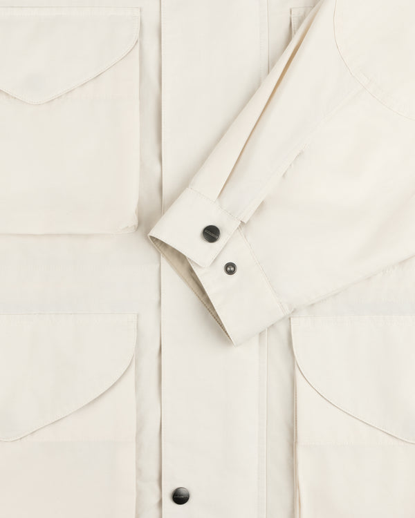 Close-up of the Lightweight Barn Jacket in cream with flap pockets and black buttoned cuffs on the sleeve.
