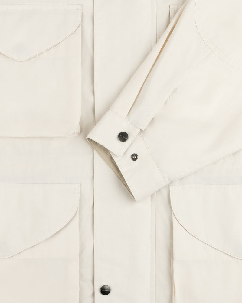 Close-up of the Lightweight Barn Jacket in cream with flap pockets and black buttoned cuffs on the sleeve.