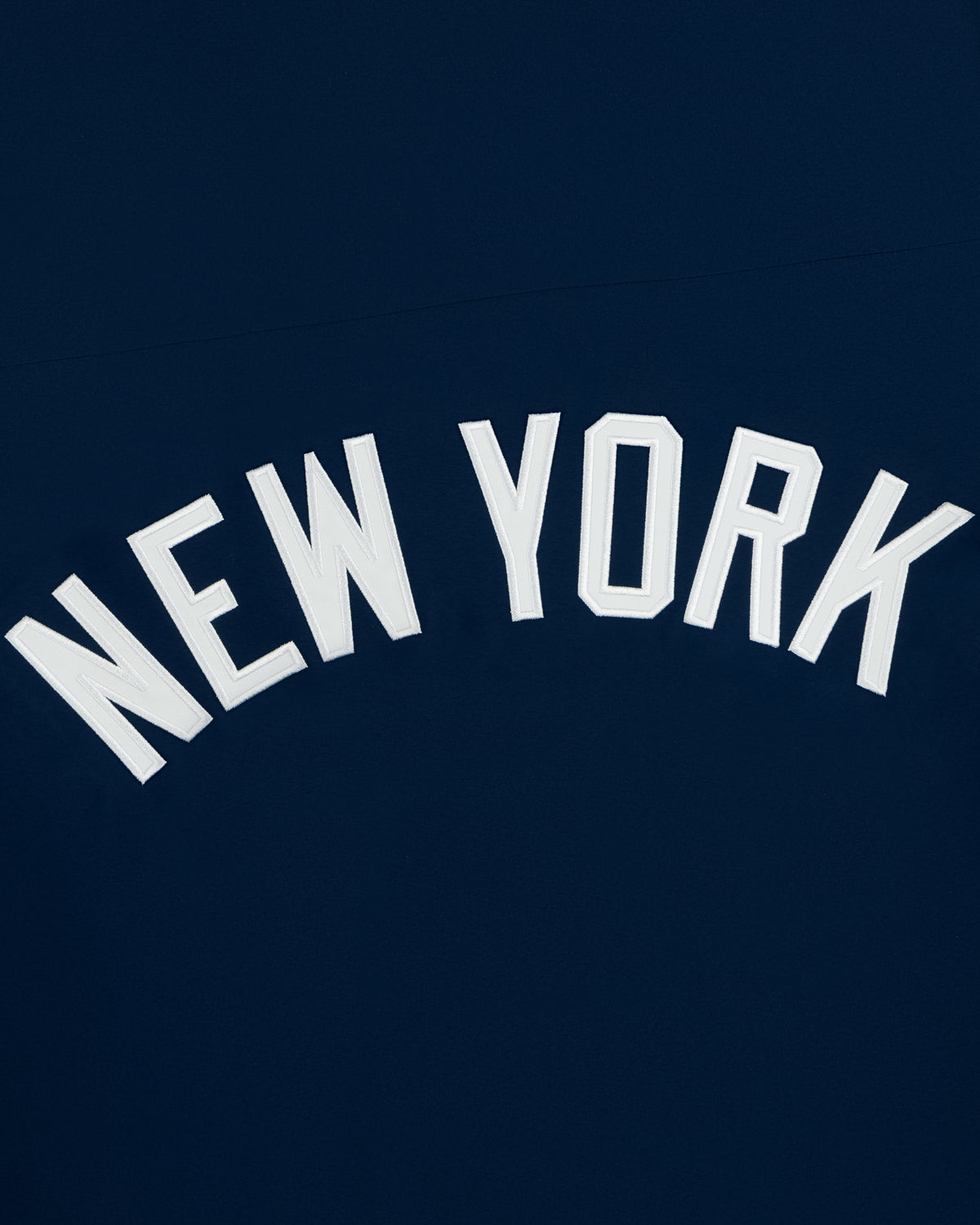 White NEW YORK text in caps on dark blue, featured on the Yankees GORE-TEX Rain Delay Jacket.