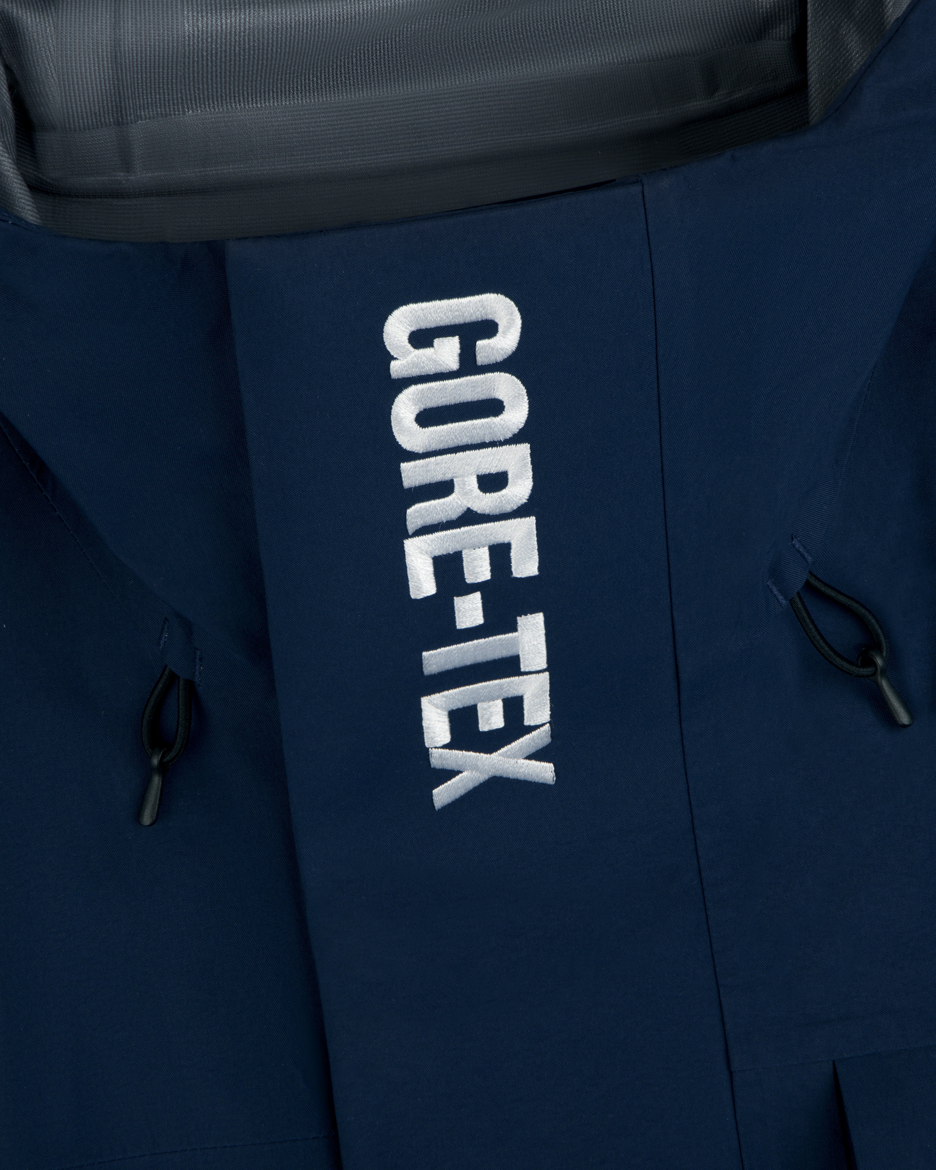 Close-up of Yankees GORE-TEX Rain Delay Jacket, blue with white GORE-TEX embroidery and black side drawstrings.