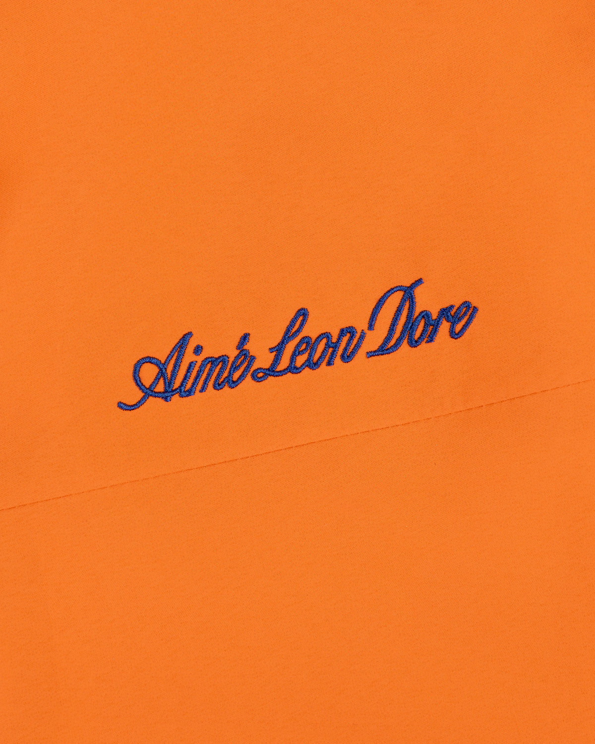 Mets GORE-TEX Rain Delay Jacket in orange with Aimé Leon Dore embroidered in blue script.