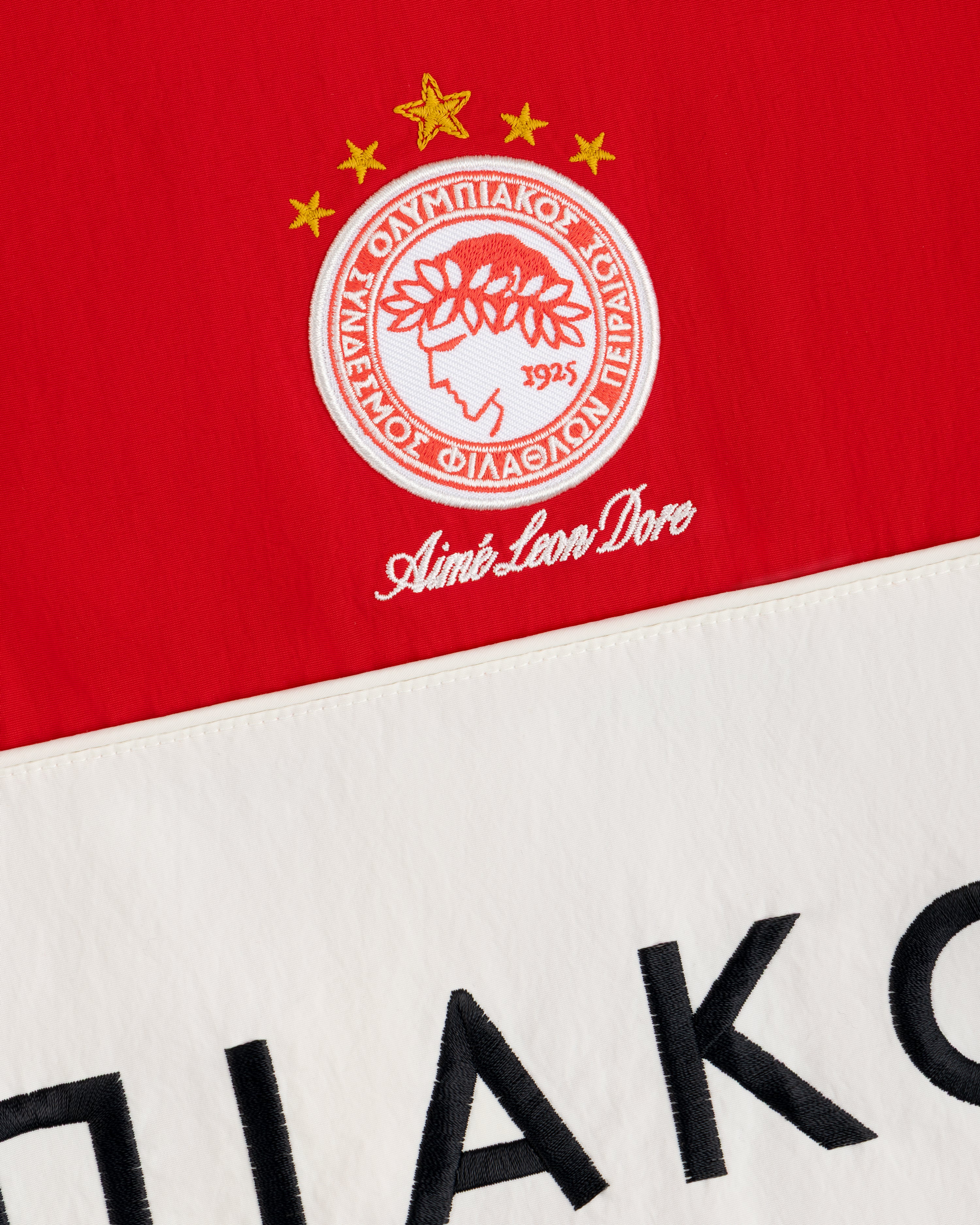 ALD / Olympiacos F.C. Nylon Quarter Zip Pullover in red and cream with an embroidered crest and black lettering.