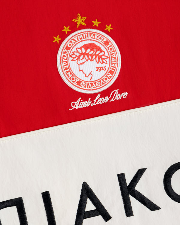 ALD / Olympiacos F.C. Nylon Quarter Zip Pullover in red and cream with an embroidered crest and black lettering.