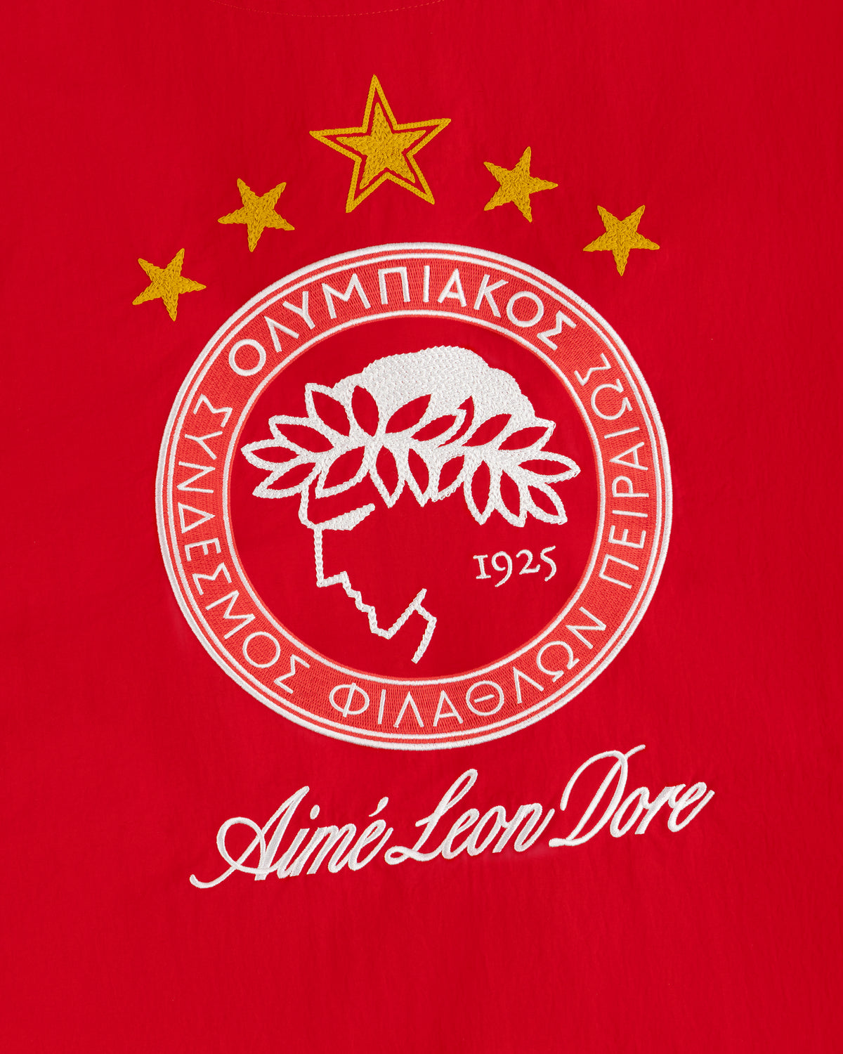 ALD / Olympiacos F.C. Nylon Quarter Zip Pullover with an embroidered crest on red fabric.