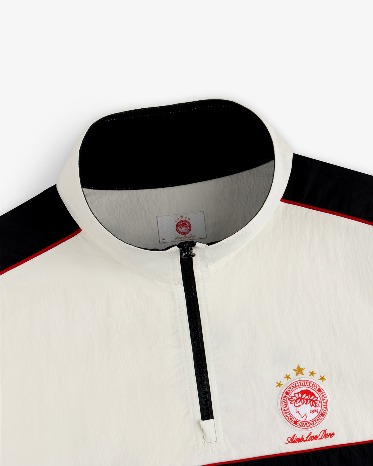 ALD / Olympiacos F.C. Nylon Quarter Zip Pullover in off-white with black accents and a red and gold sports emblem.