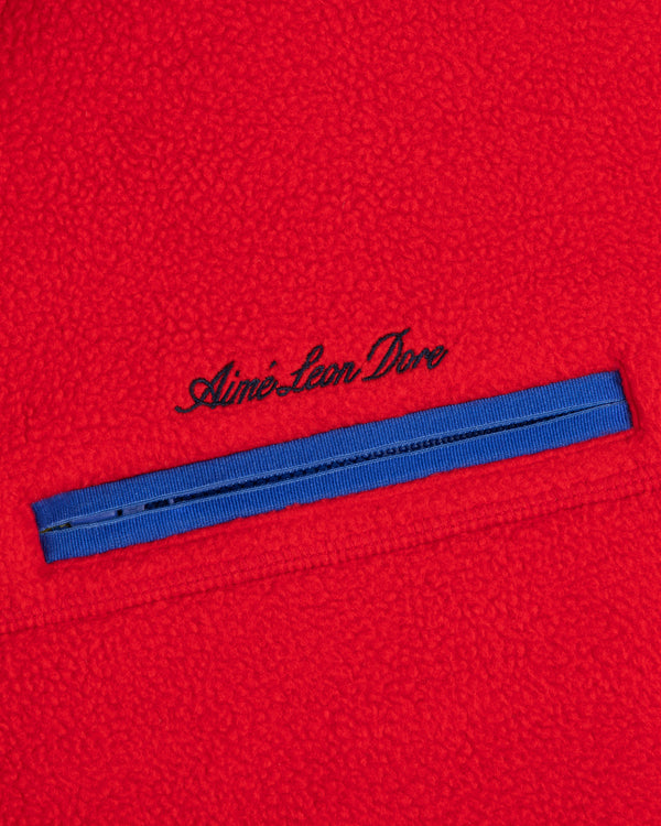 Red Script Fleece Half Zip Pullover with a blue zippered chest pocket and embroidered text above the zipper.